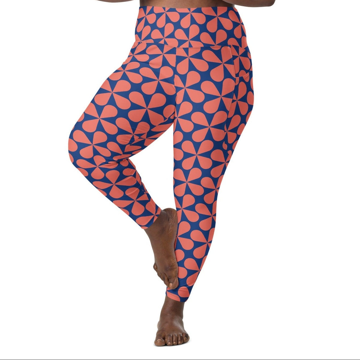 Model wearing the  Bakerloo Sculpt Leggings in geometric pattern in blue with coral background.