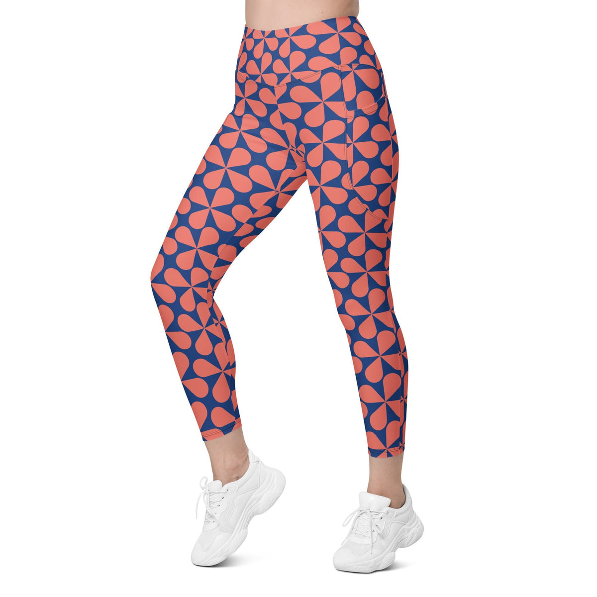 Model wearing the  Bakerloo Sculpt Leggings in geometric pattern in blue with coral background.
