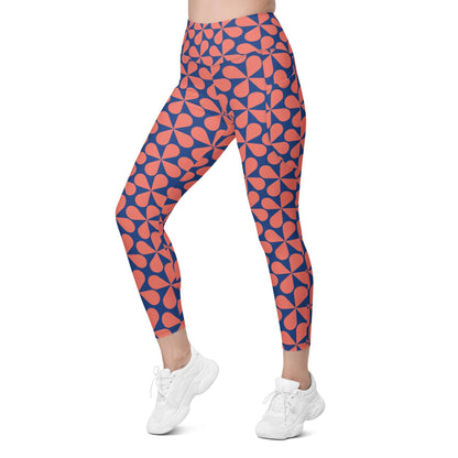 Model wearing the  Bakerloo Sculpt Leggings in geometric pattern in blue with coral background.