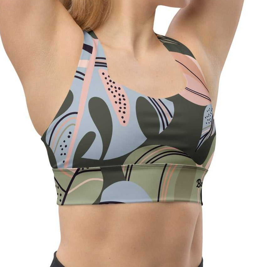 A model wearing The Barbican Longline Performance Bra, showing the supportive longline cut and the pastel green and pink exotic flower print.