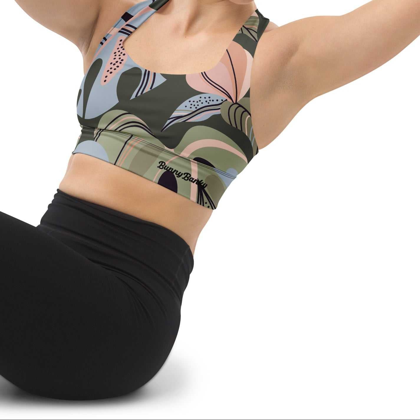 A model wearing The Barbican Longline Performance Bra, showing the supportive longline cut and the pastel green and pink exotic flower print.