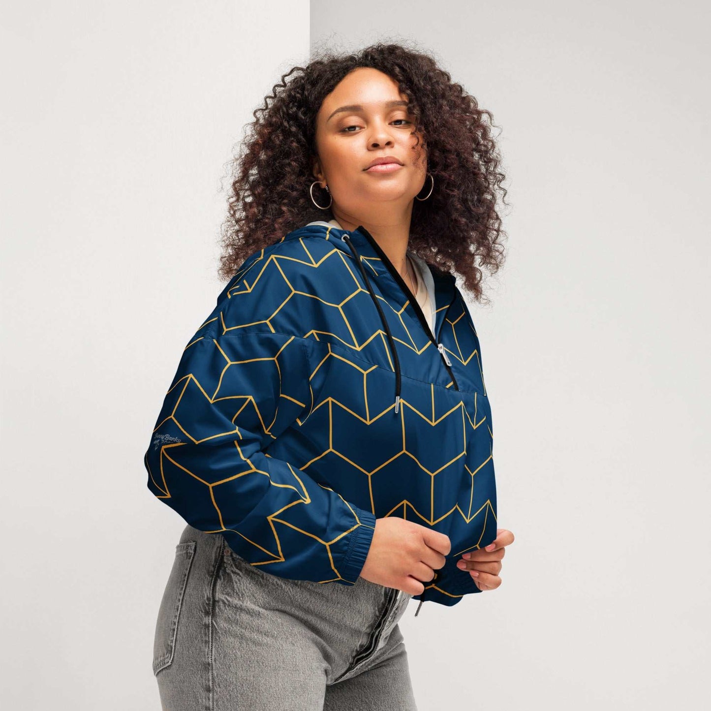 A model wearing The Baron's Court Windbreaker, showing the lightweight jacket's fit and the signature navy blue and yellow Art Deco print.
