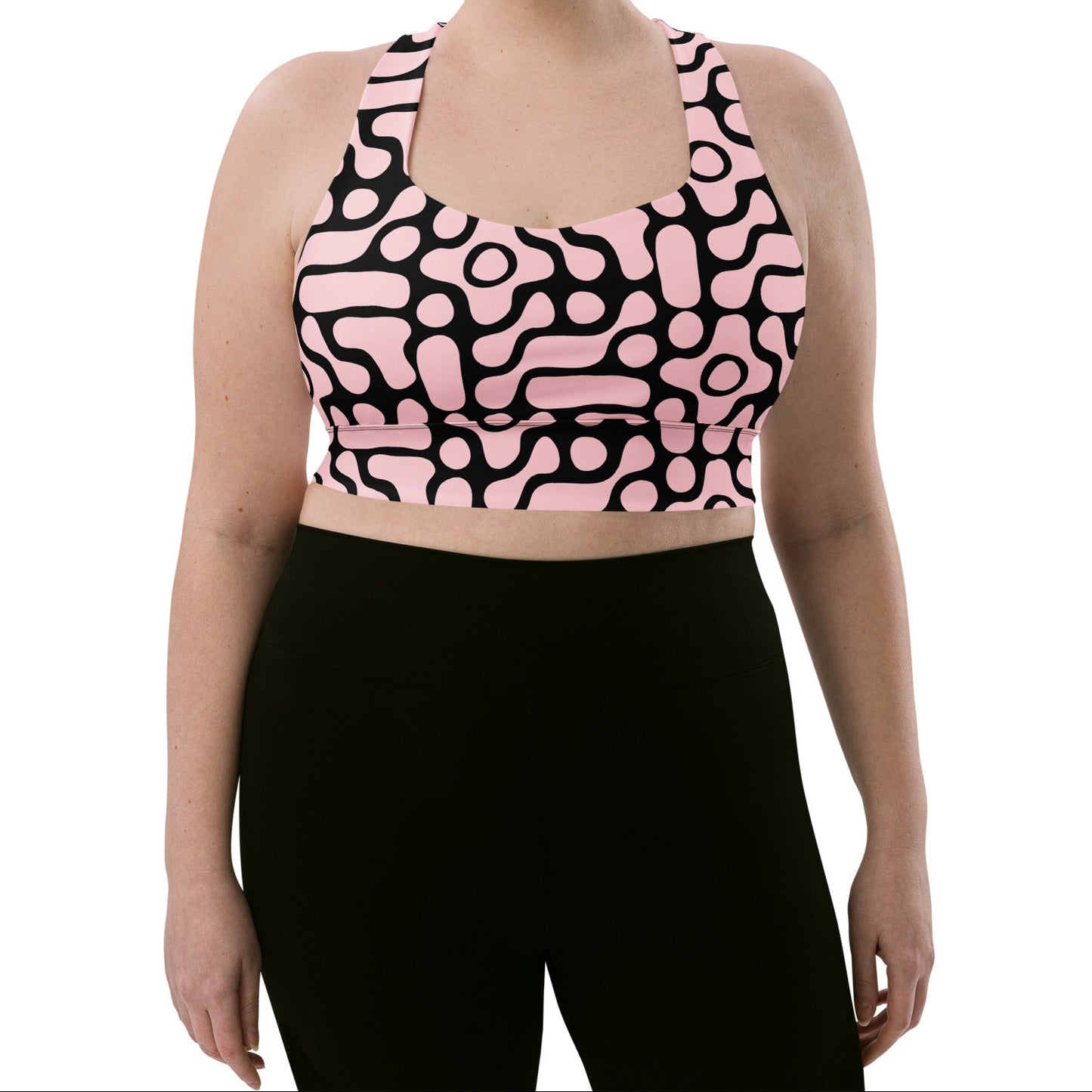 A model wearing the Berlin Performance Bra in black geometric floral pattern on pink background