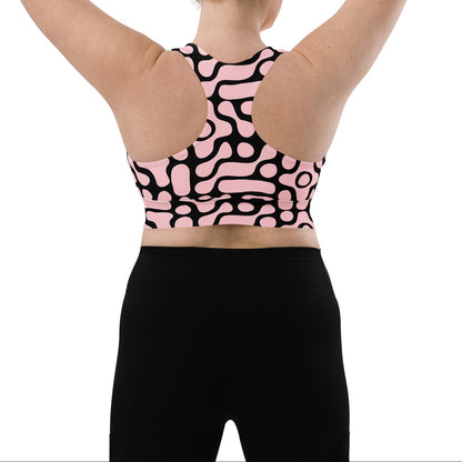 A model wearing the Berlin Performance Bra in black geometric floral pattern on pink background