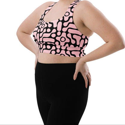 A model wearing the Berlin Performance Bra in black geometric floral pattern on pink background