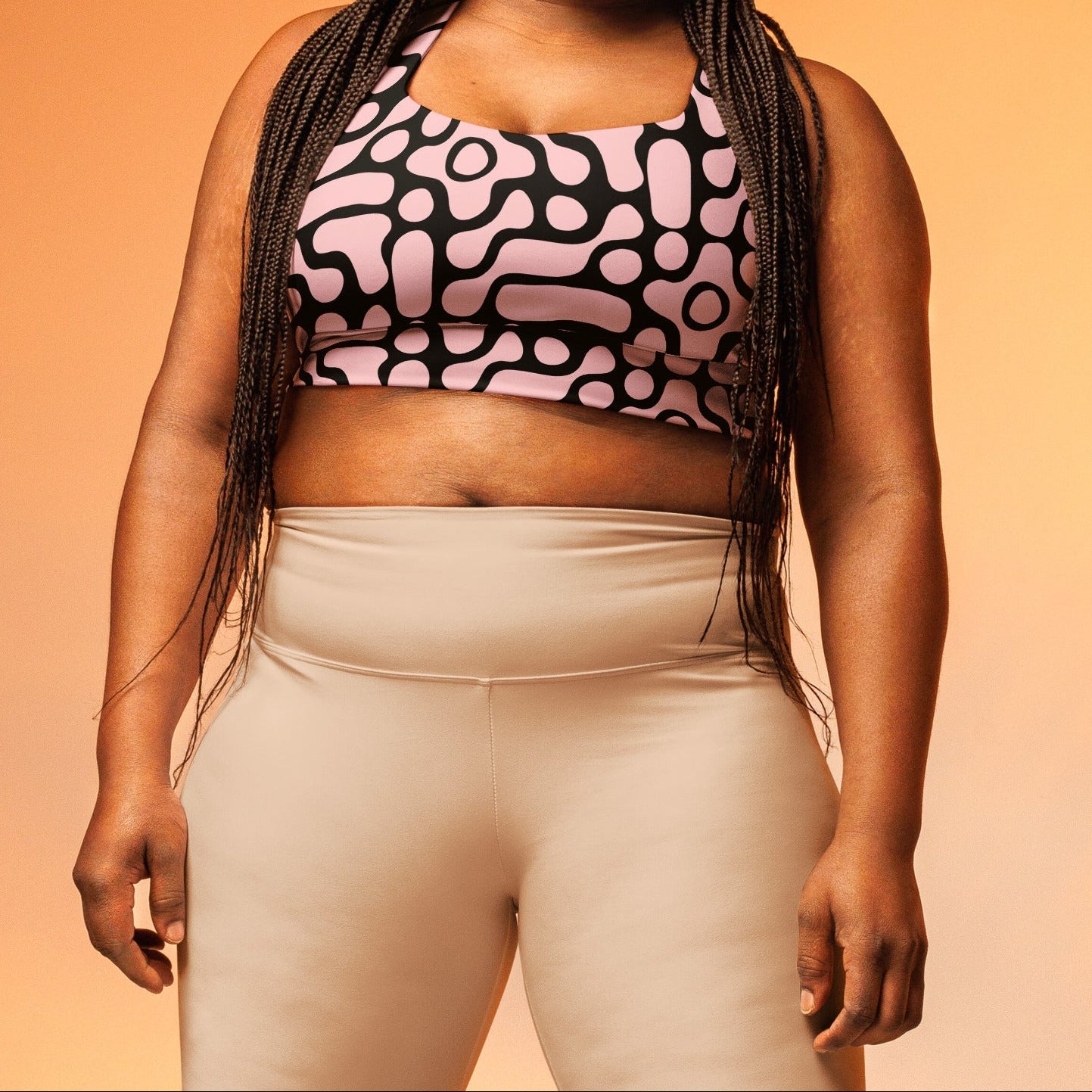 A model wearing the Berlin Performance Bra in black geometric floral pattern on pink background