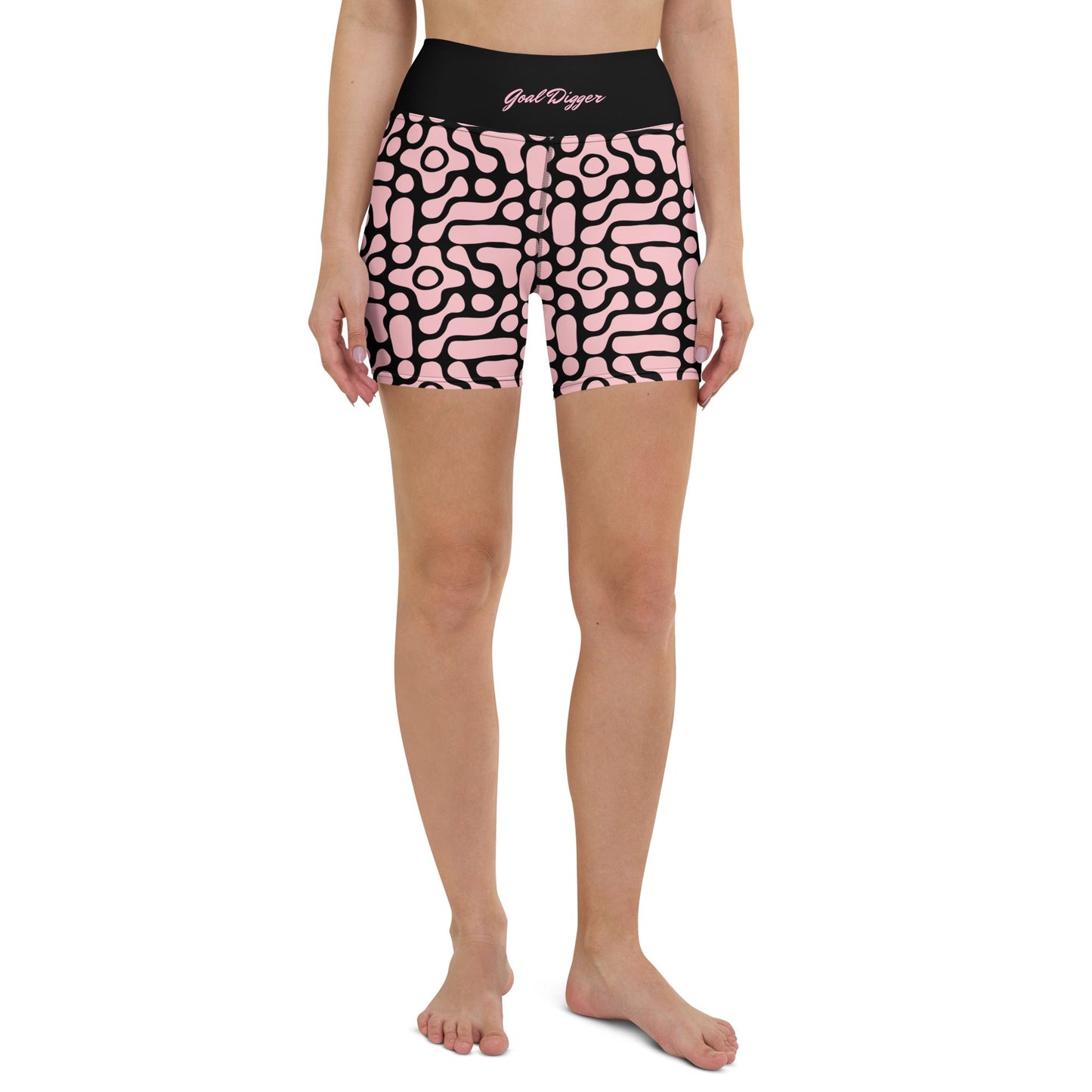 A close-up front view of BunnyBanky performance shorts featuring a bold, custom-designed geometric black floral pattern on a soft pink base. The high-waisted black compression waistband prominently displays the text "GOAL DIGGER" in a stylised, matching pink font. The shorts are designed for a snug, performance fit, shown here as part of a coordinated athletic set against a solid pink studio background.