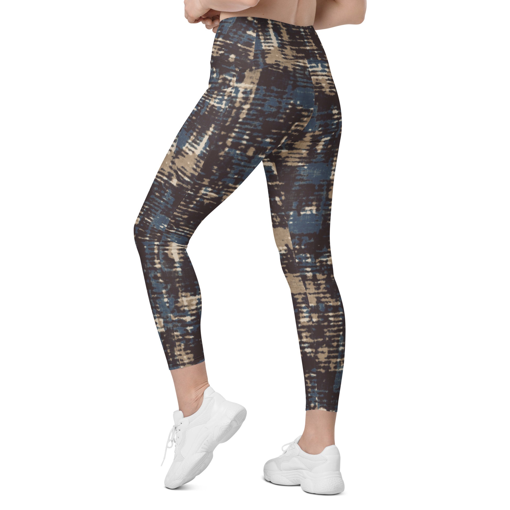 A model wearing the Chamonix Sculpt Leggings. A high-waisted leggings with an abstract brushstroke pattern in blue, beige, and dark brown, paired with white sneakers, shown against a plain white background.