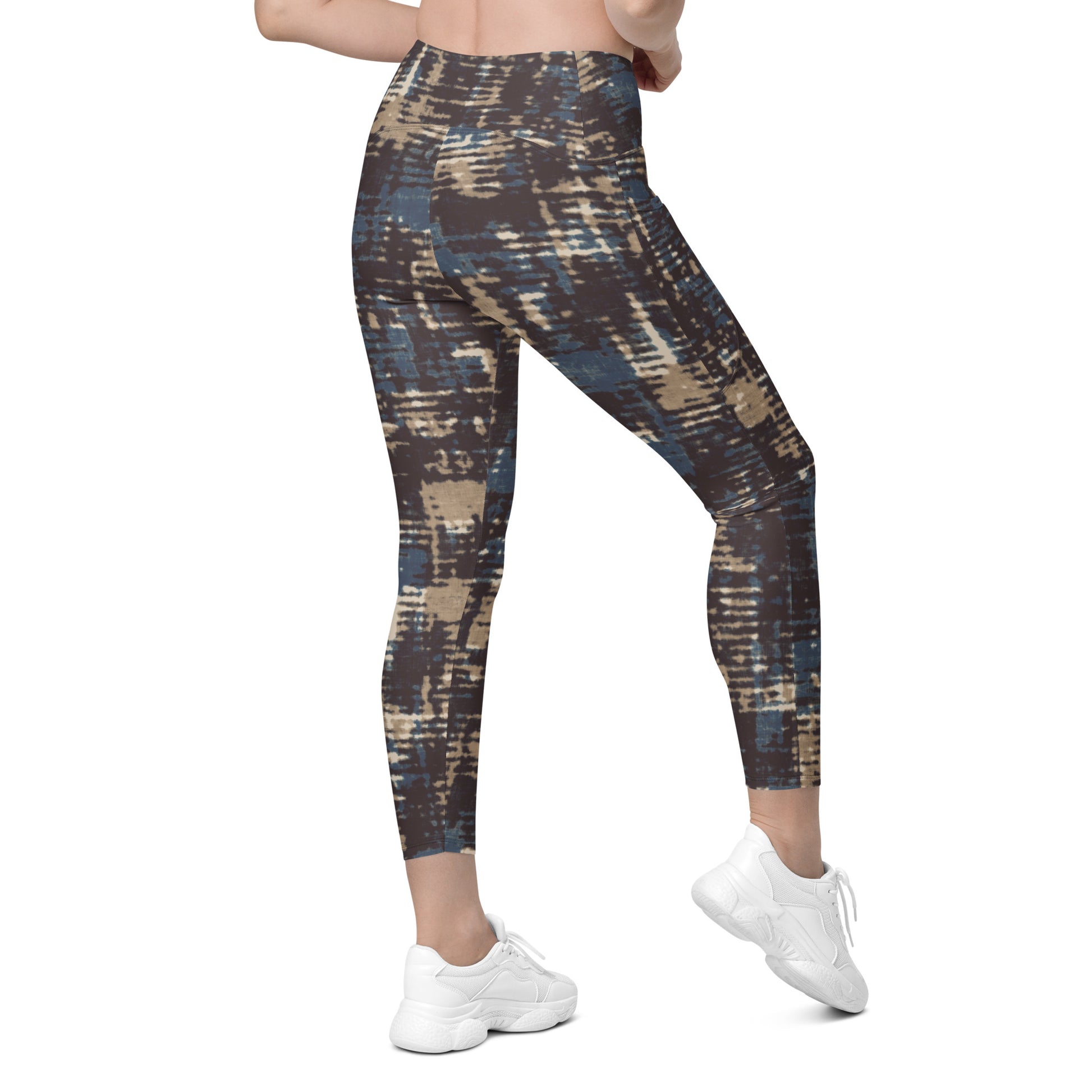 A model wearing the Chamonix Sculpt Leggings. A high-waisted leggings with an abstract brushstroke pattern in blue, beige, and dark brown, paired with white sneakers, shown against a plain white background.