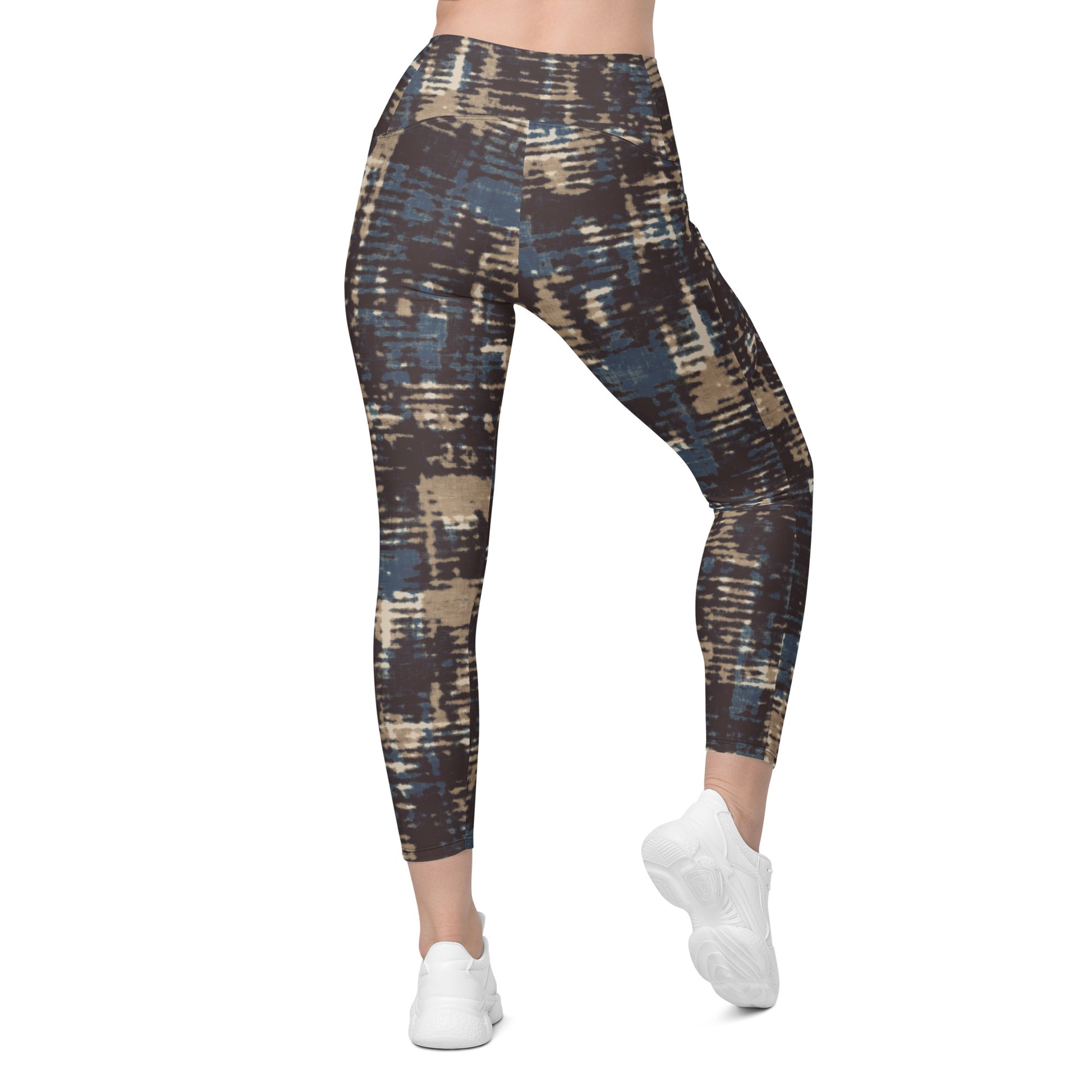 A model wearing the Chamonix Sculpt Leggings. A high-waisted leggings with an abstract brushstroke pattern in blue, beige, and dark brown, paired with white sneakers, shown against a plain white background.