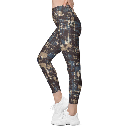 A model wearing the Chamonix Sculpt Leggings. A high-waisted leggings with an abstract brushstroke pattern in blue, beige, and dark brown, paired with white sneakers, shown against a plain white background.