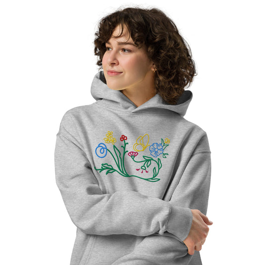 A model wearing The Chelsea Garden Oversized Hoodie, showing the relaxed fit and the large, intricate floral arrangement embroidered across the chest.