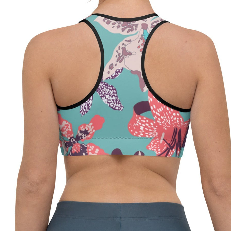 Model wearing the Chelsea Performance Bra high-compression performance sports bra featuring a vibrant tropical floral print in turquoise and pink and racer back.
