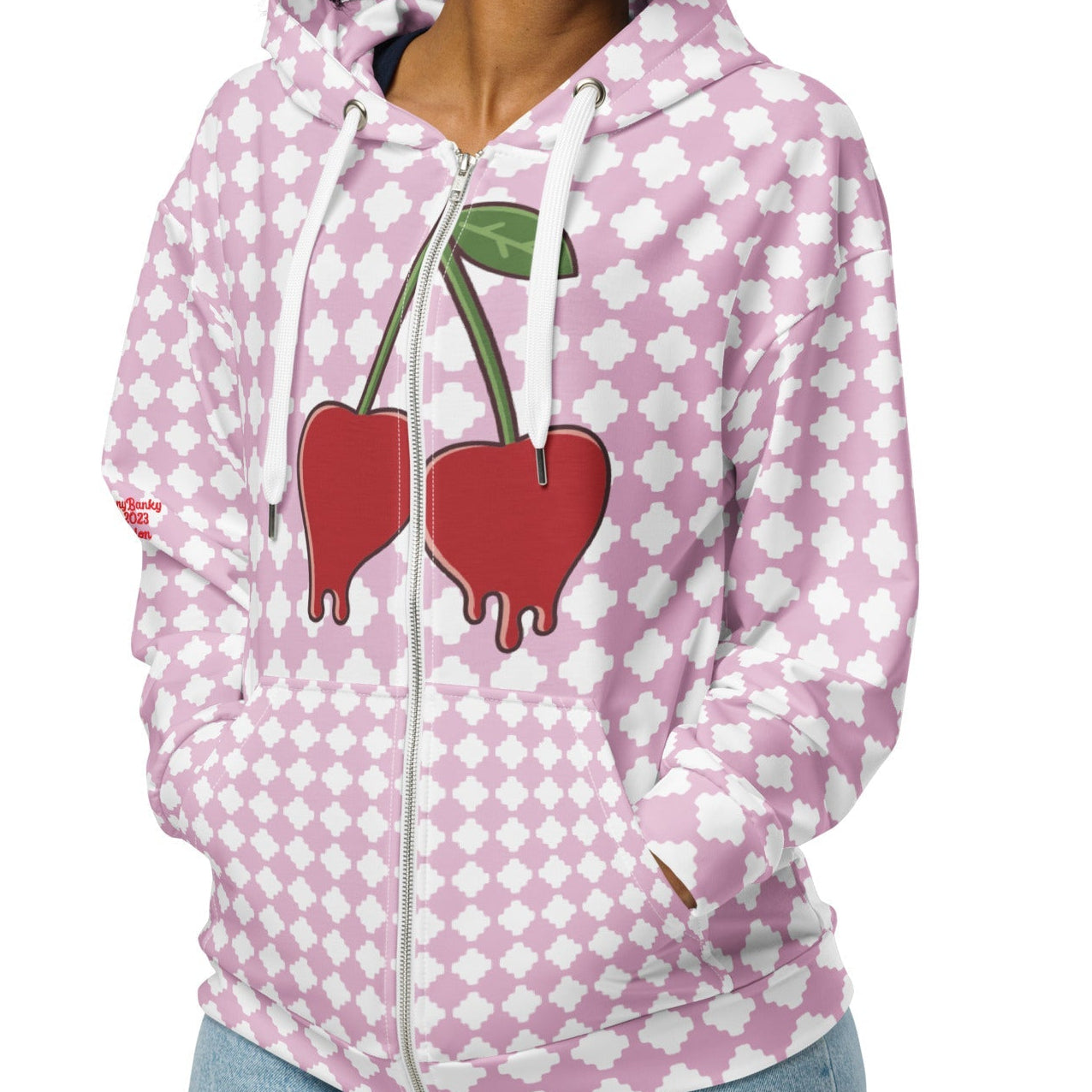 A BunnyBankY zip hoodie featuring a pink and white geometric clover pattern, a dripping heart-cherry graphic on the front, and 