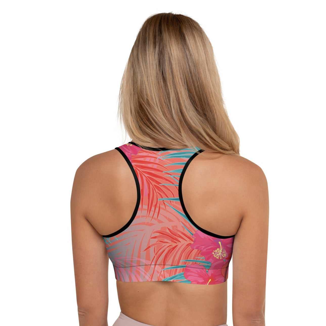 Close-up of a  model wearing the District Tropics Performance Bra. The image showcases the vibrant pink and blue floral pattern, the supportive racerback design, and the premium mesh lining details.