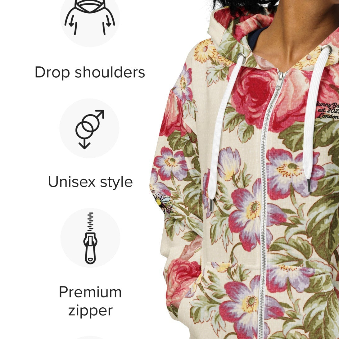 A model wearing the Evergreen Zip Hoodie, showcasing the elaborate red rose and green vine vintage print on a sustainable cream fabric.