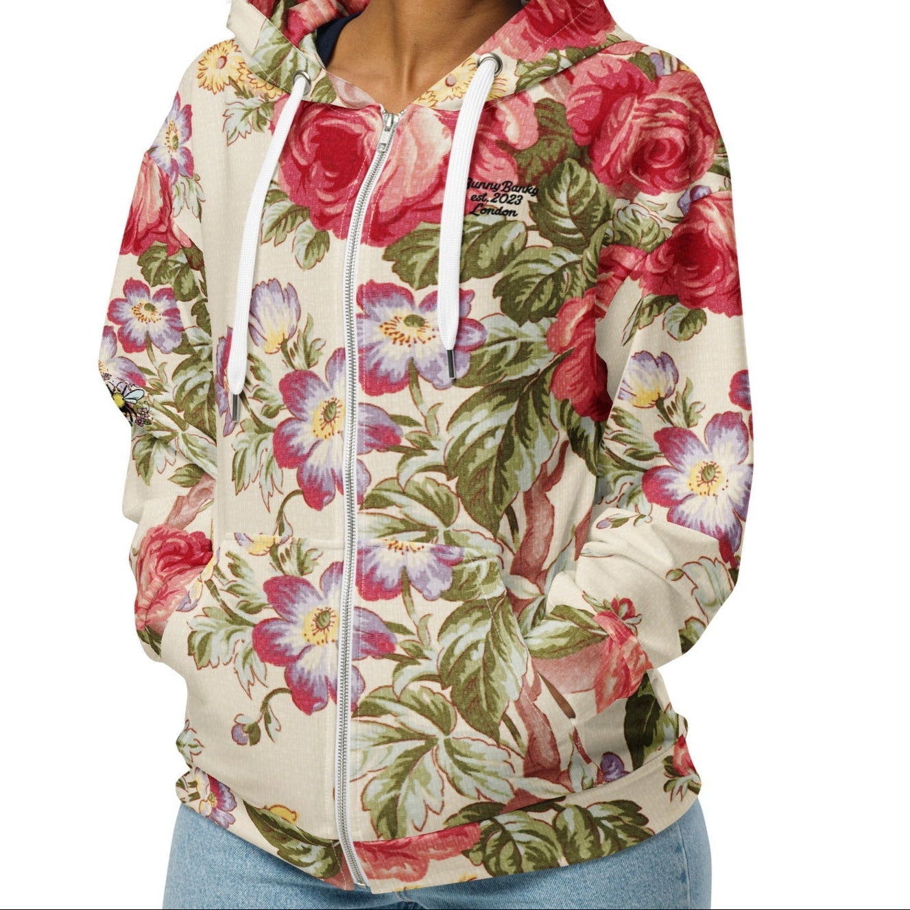 A model wearing the Evergreen Zip Hoodie, showcasing the elaborate red rose and green vine vintage print on a sustainable cream fabric.