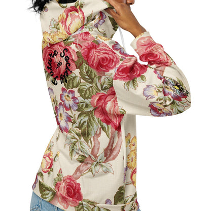 A model wearing the Evergreen Zip Hoodie, showcasing the elaborate red rose and green vine vintage print on a sustainable cream fabric.