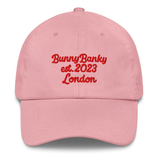 A close up of The Heritage Cap in pink showing the heriatage branded signature embroidered in red