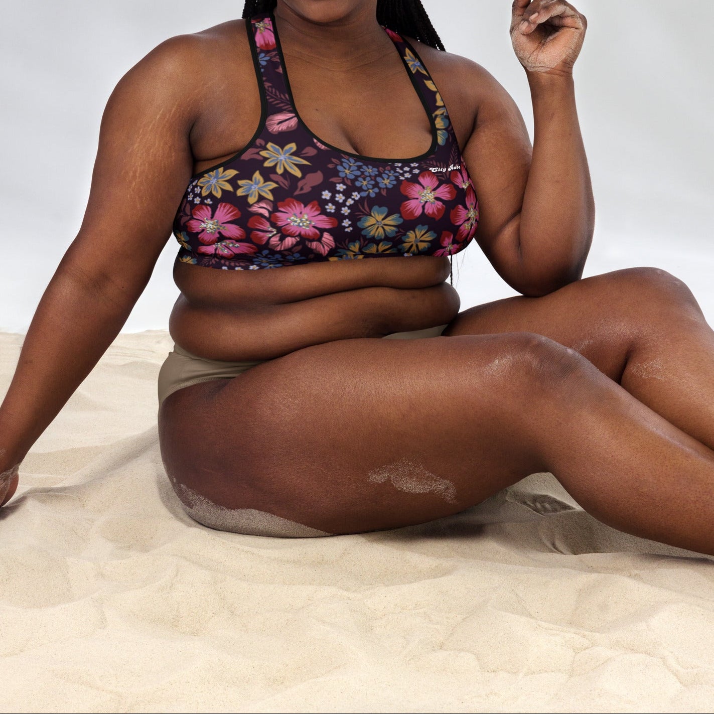A model wearing the Green Park Performance Bra in blue, pink, yellow floral pattern on burgundy background