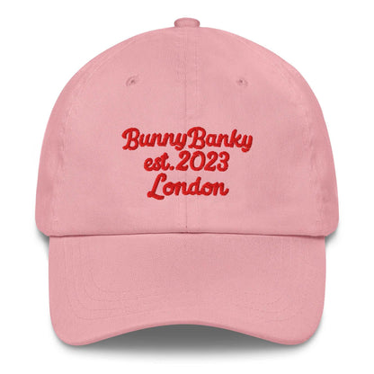 A close up of The Heritage Cap in pink showing the heritage branded signature embroidered in red