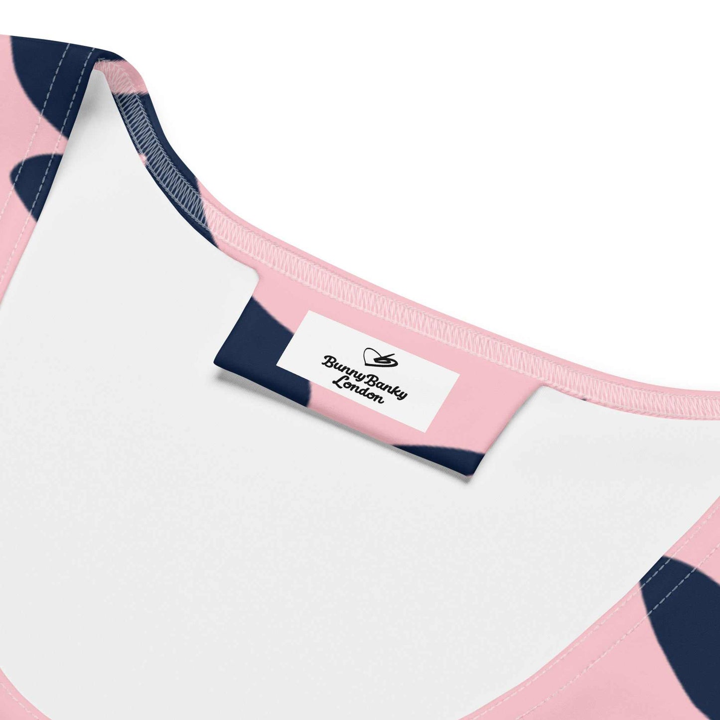 A close up of the Kensington Performance Tank featuring navy blue floral pattern on soft pink fabric inside branded label.