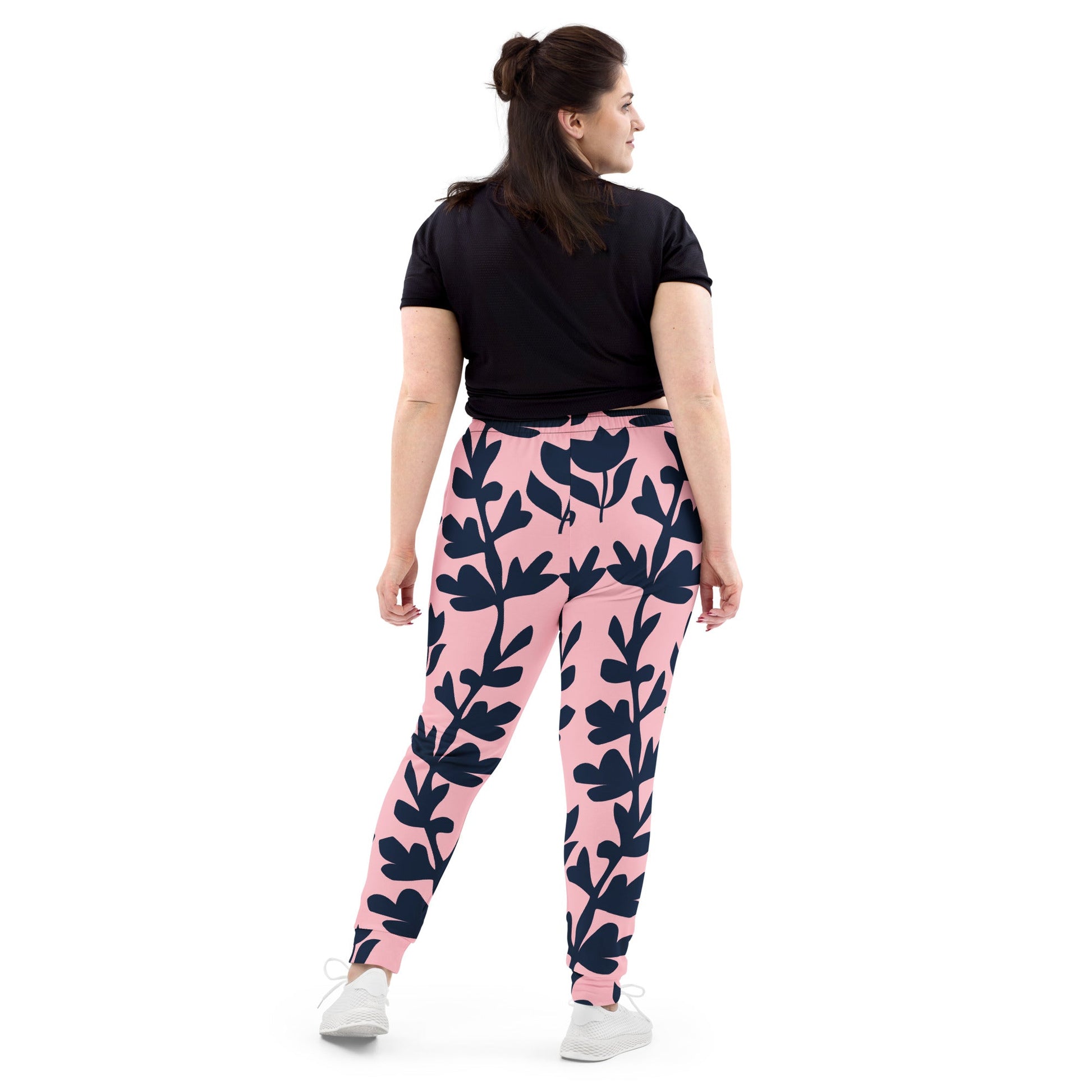 A model wearing The Kensington Glide Joggers, showing the slim fit and the bold, high-contrast pink and blue oversized floral print.