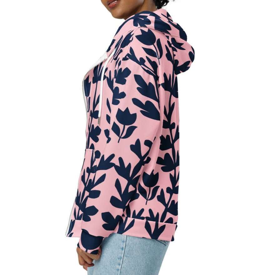 A model wearing The Kensington Zip Hoodie, showing the full-zip closure and the oversized pink and blue floral print across the recycled polyester fabric.
