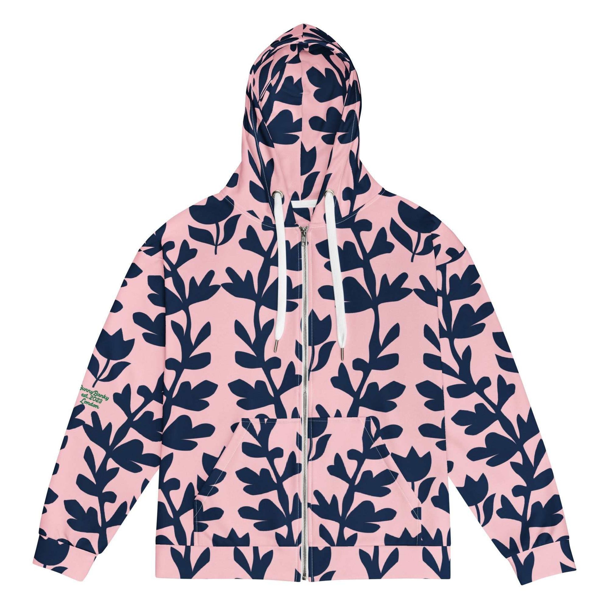 A model wearing The Kensington Zip Hoodie, showing the full-zip closure and the oversized pink and blue floral print across the recycled polyester fabric.
