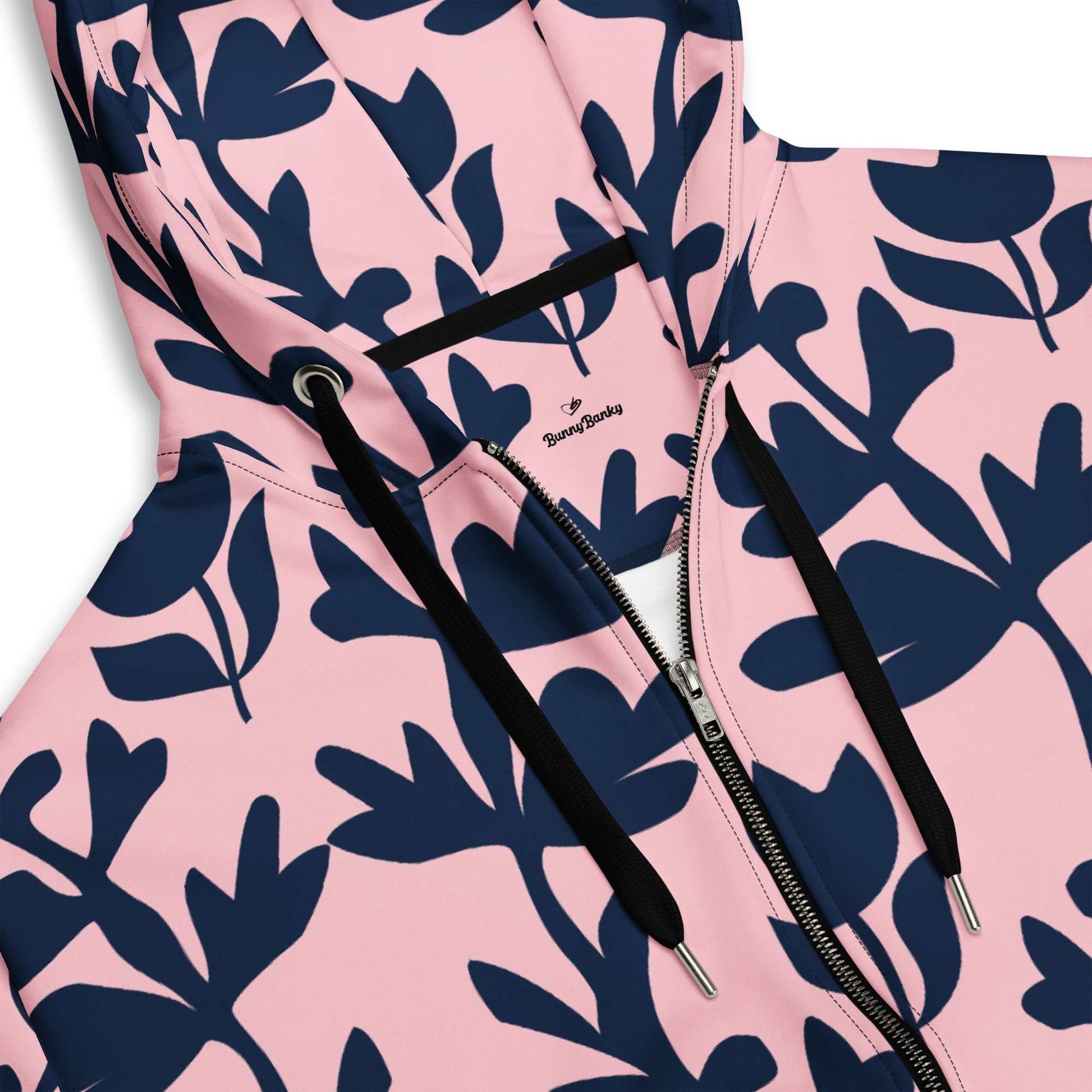 A model wearing The Kensington Zip Hoodie, showing the full-zip closure and the oversized pink and blue floral print across the recycled polyester fabric.
