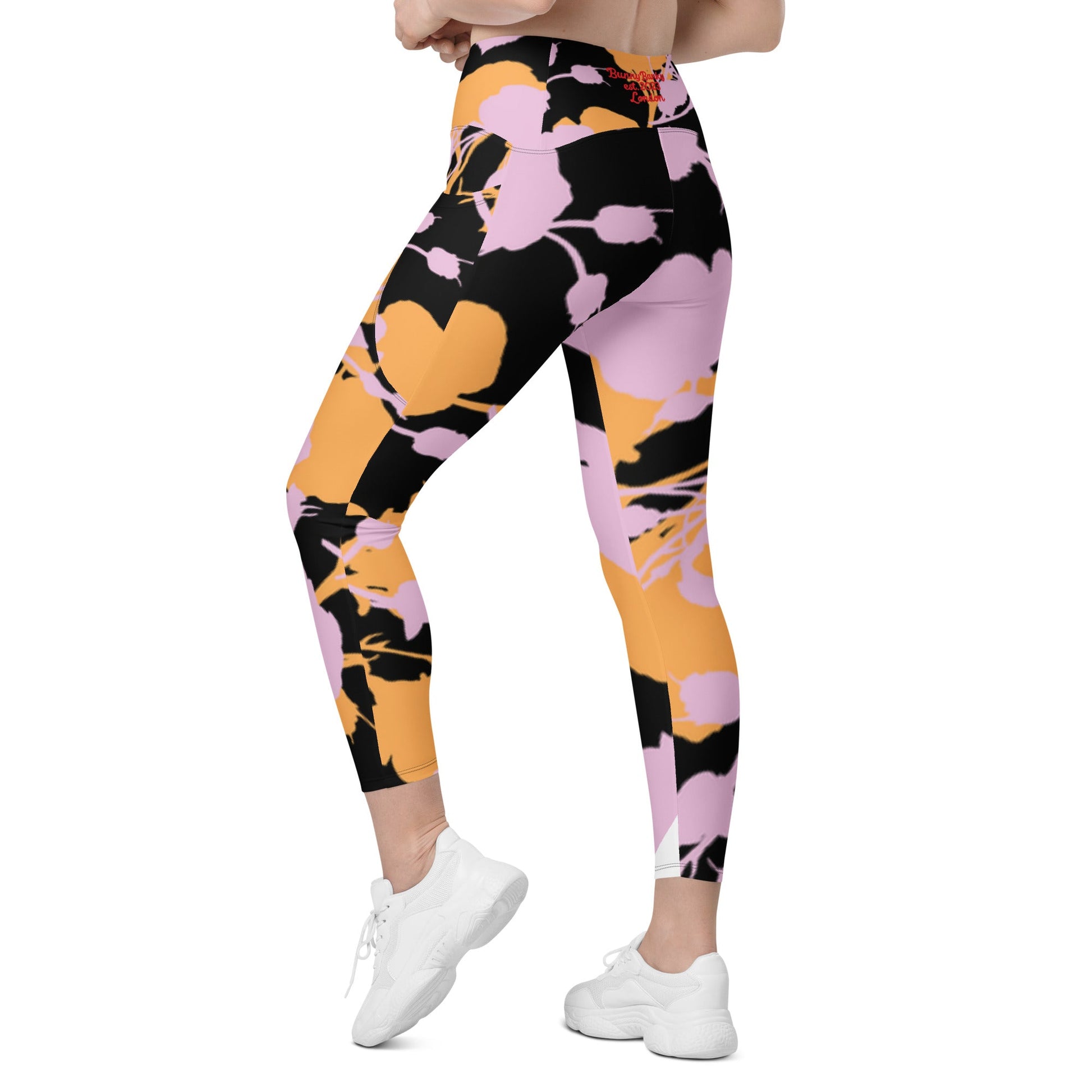 A model wearing The Miami Sculpt Leggings, showing the sculpting fit and the dynamic pink and orange splashes print on the black fabric.
