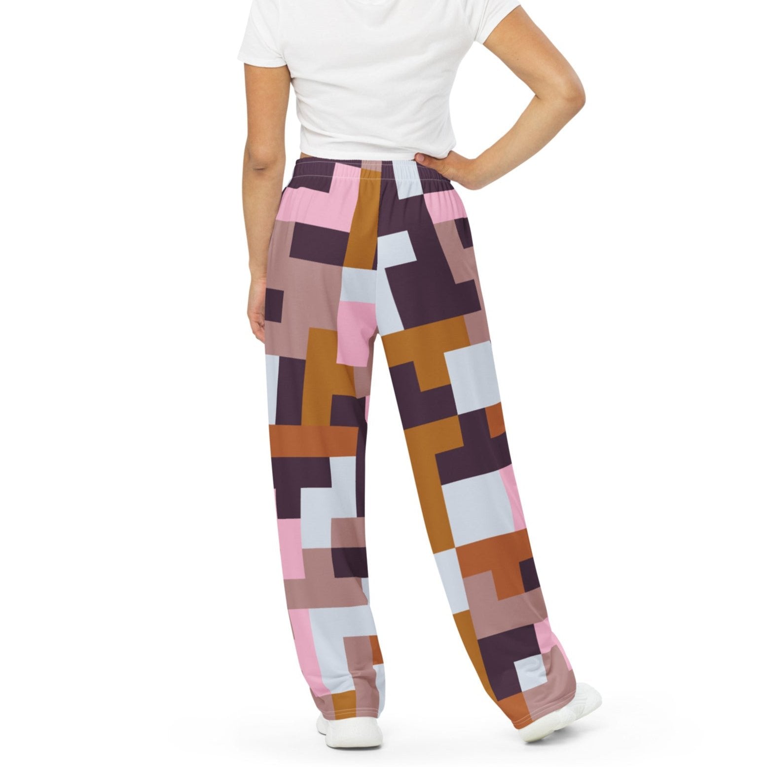 Model wearing the Marais Flow Joggers. These joggers are high-waisted, wide-leg flowy joggers featuring the distinctive cubism-inspired geometric pattern made of interlocking pink, brown, dark purple, and white rectangular and square blocks. 