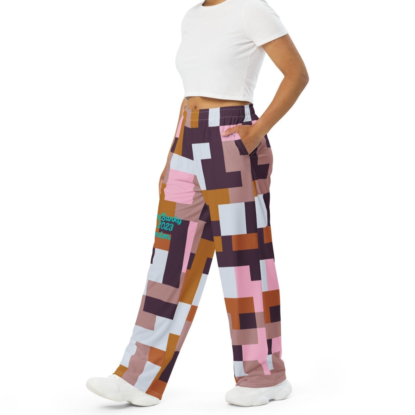 Model wearing the Marais Flow Joggers. These joggers are high-waisted, wide-leg flowy joggers featuring the distinctive cubism-inspired geometric pattern made of interlocking pink, brown, dark purple, and white rectangular and square blocks. 
