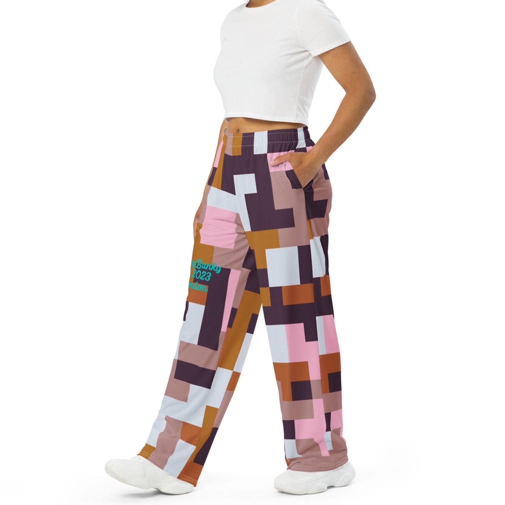 Model wearing the Marais Flow Joggers. These joggers are high-waisted, wide-leg flowy joggers featuring the distinctive cubism-inspired geometric pattern made of interlocking pink, brown, dark purple, and white rectangular and square blocks. 