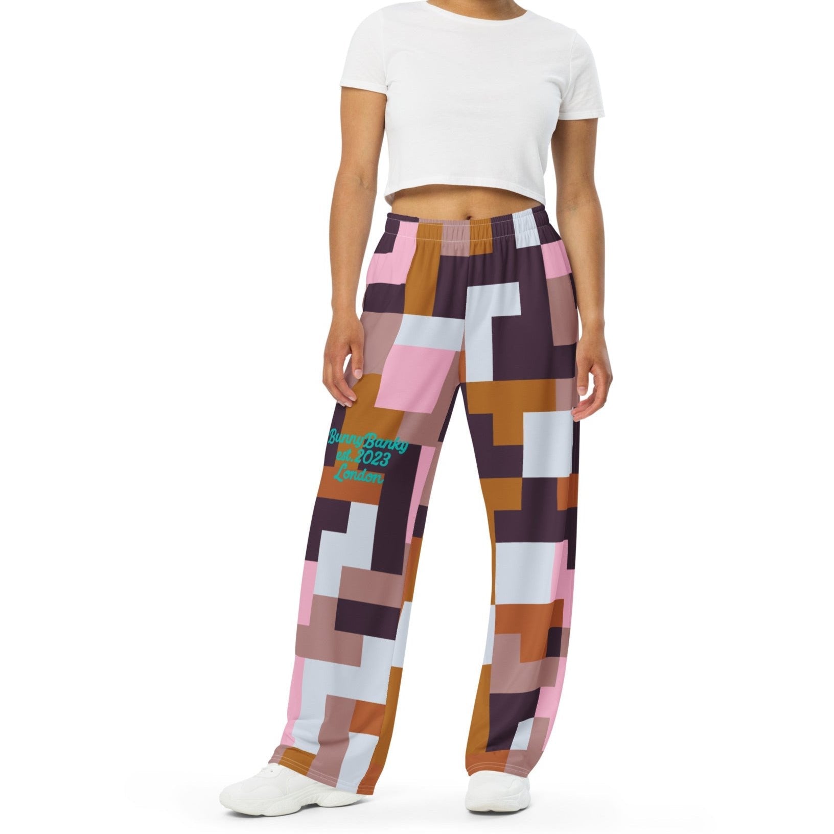Model wearing the Marais Flow Joggers. These joggers are high-waisted, wide-leg flowy joggers featuring the distinctive cubism-inspired geometric pattern made of interlocking pink, brown, dark purple, and white rectangular and square blocks. 