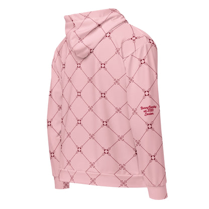 Close-up of the Mayfair Hoodie's fabric, highlighting the precise burgundy geometric monogram inspired effect on the pink background, the heritage signature in red on the sleeve and the soft texture of the 95% certified recycled polyester.