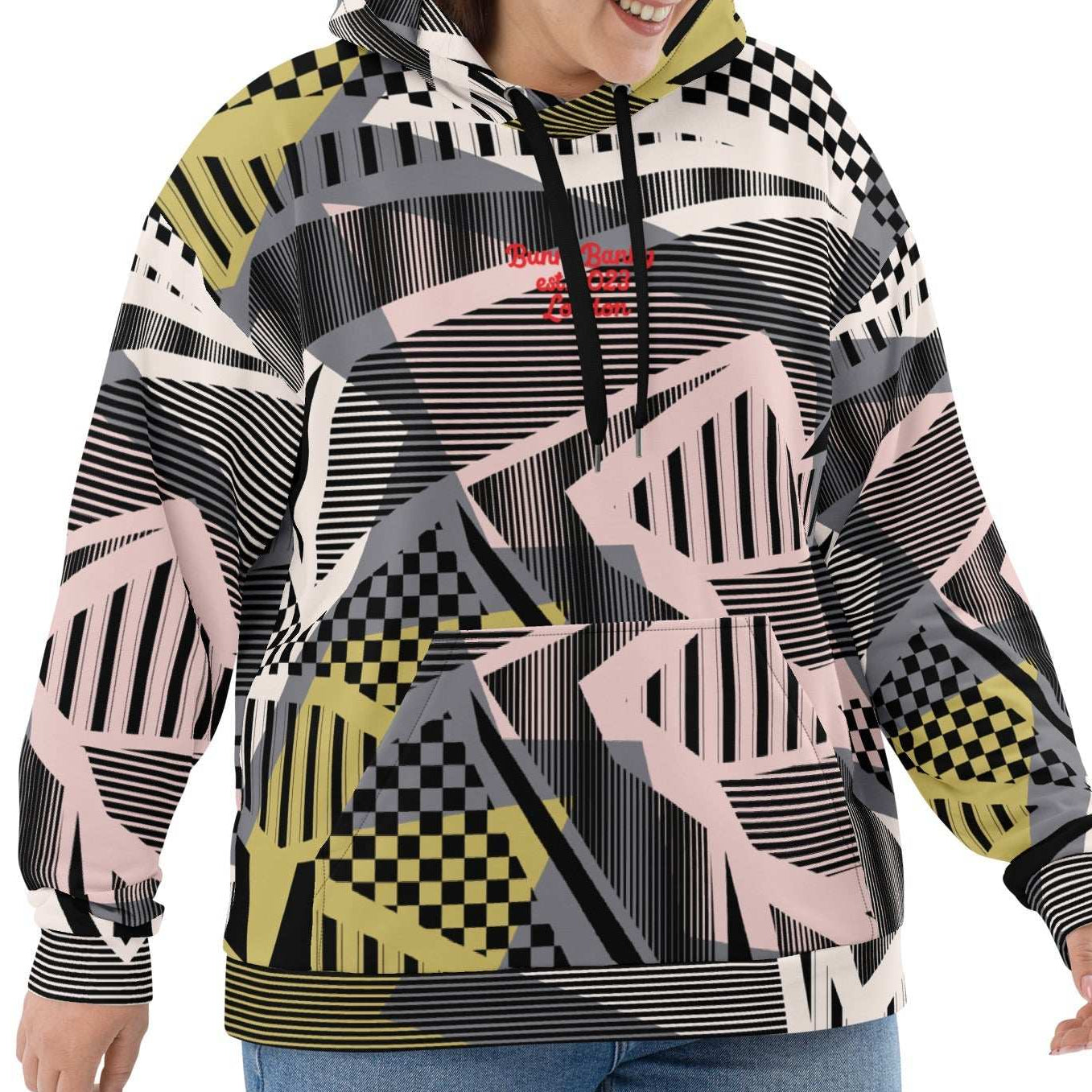 A  model wearing the Miami Resort Hoodie. The image highlights the Art Deco-inspired pattern of checkers and pinstripes in soft pink, sand, and olive tones, featuring red London branding.