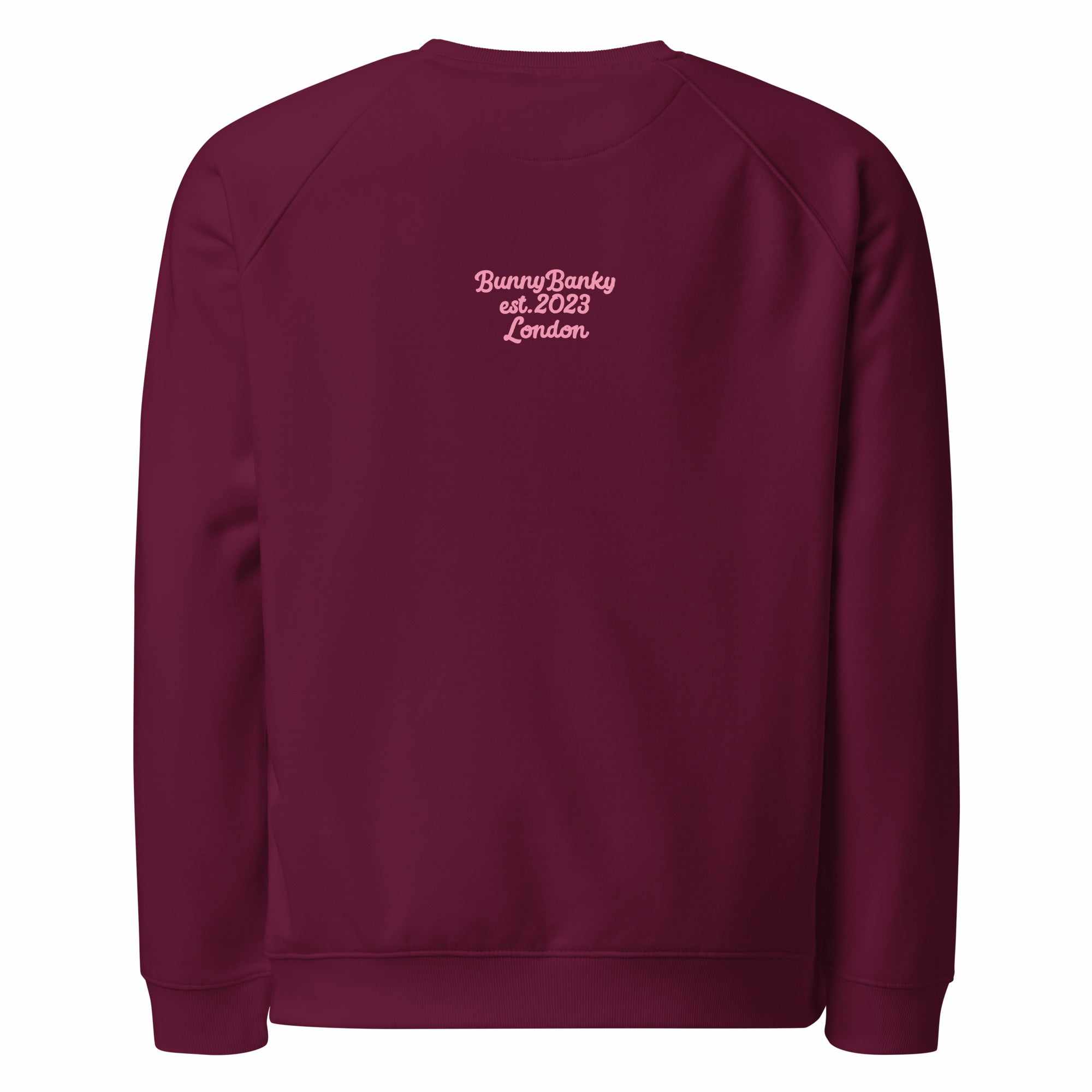 A close-up of The Monument Organic Sweatshirt, showing the detailed embroidery of a vibrant pink heart with wings on the 100% organic cotton fabric.