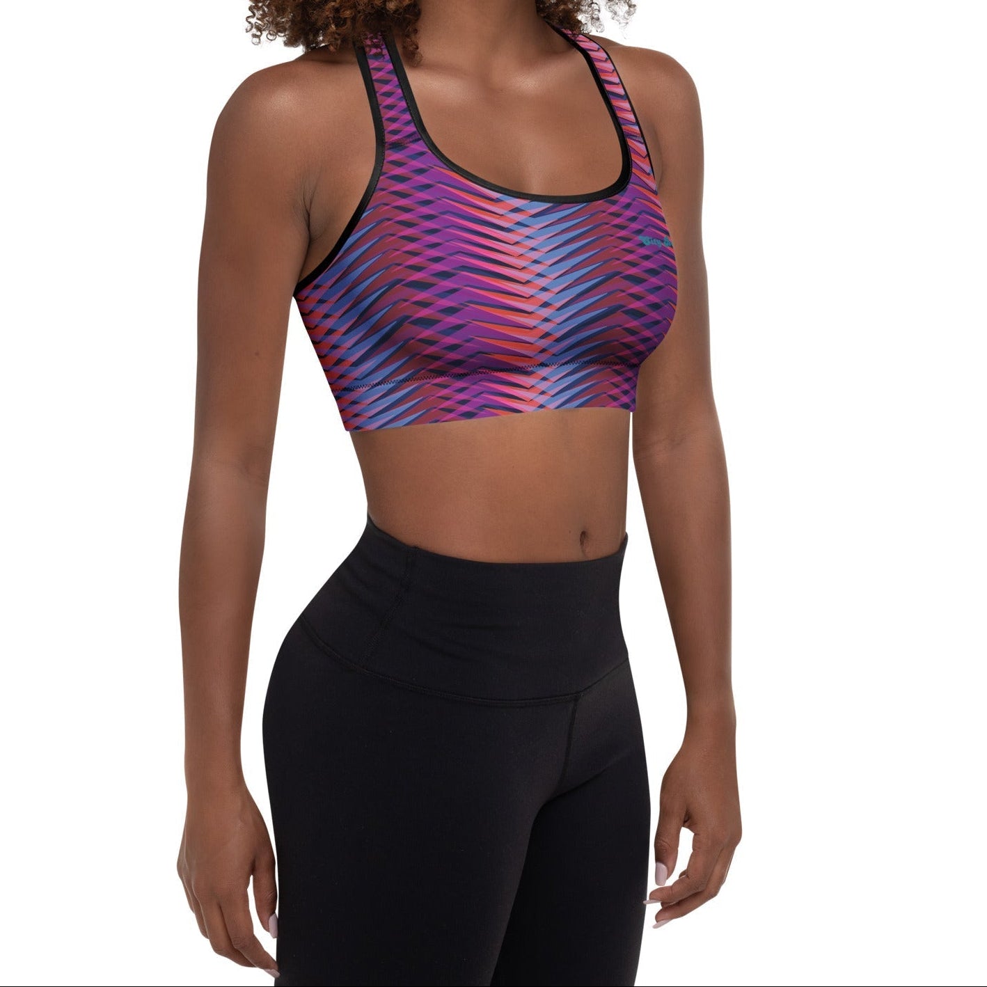 A model wearing The Moorgate Performance Bra, showing the supportive fit and the dynamic graphic arrow print in vibrant pink, orange, and blue hues.