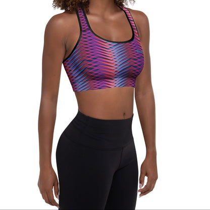 A model wearing The Moorgate Performance Bra, showing the supportive fit and the dynamic graphic arrow print in vibrant pink, orange, and blue hues.