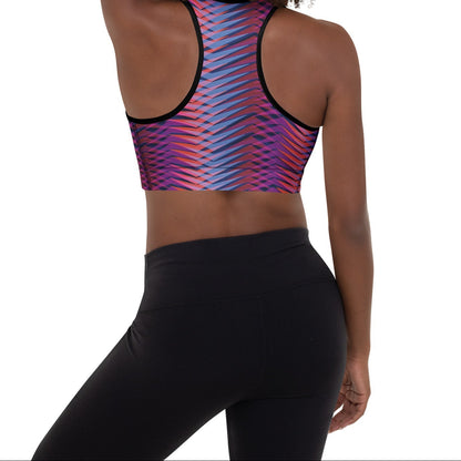A model wearing The Moorgate Performance Bra, showing the supportive fit and the dynamic graphic arrow print in vibrant pink, orange, and blue hues.