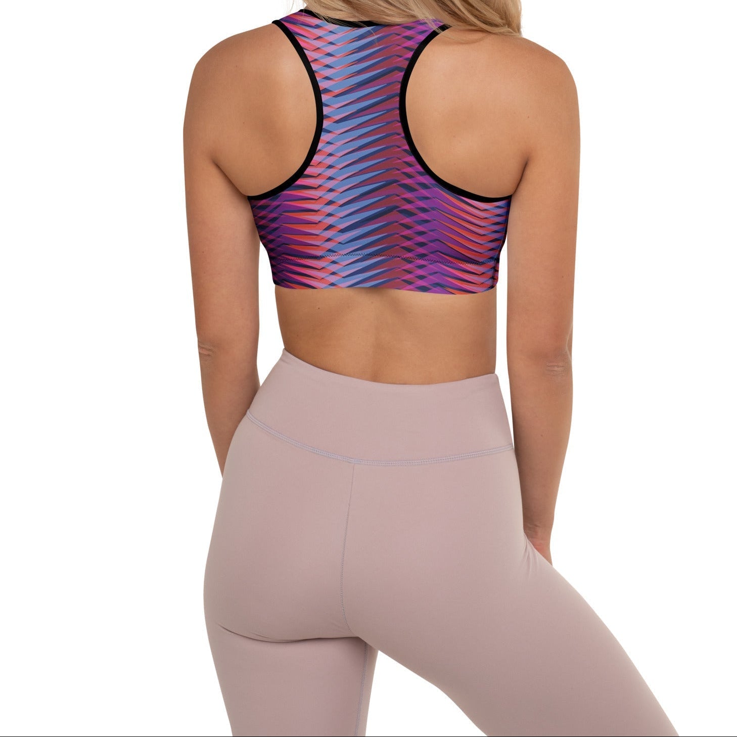 A model wearing The Moorgate Performance Bra, showing the supportive fit and the dynamic graphic arrow print in vibrant pink, orange, and blue hues.