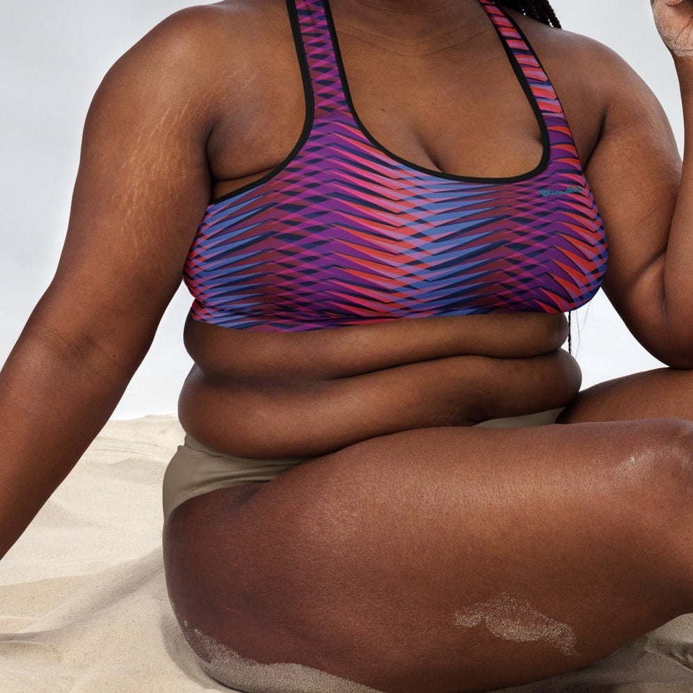 A model wearing The Moorgate Performance Bra, showing the supportive fit and the dynamic graphic arrow print in vibrant pink, orange, and blue hues.