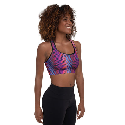 A model wearing The Moorgate Performance Bra, showing the supportive fit and the dynamic graphic arrow print in vibrant pink, orange, and blue hues.