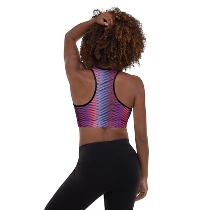 A model wearing The Moorgate Performance Bra, showing the supportive fit and the dynamic graphic arrow print in vibrant pink, orange, and blue hues.