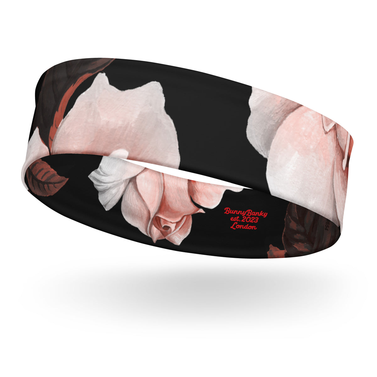 The Paris headband is an elastic featuring a floral print with pale pink and white flowers on a solid black background.