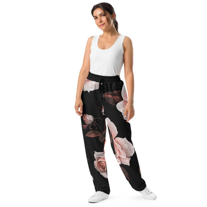 A model wearing The Paris Flow Wide Joggers, showing the wide-leg cut and the dramatic XL pale pink rose print.