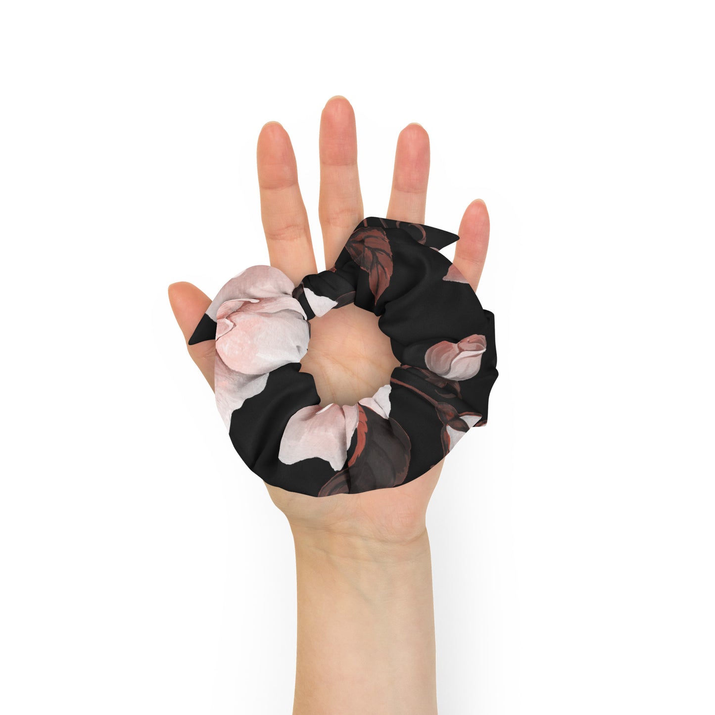 The Paris Scrunchie.A recycled fabric hair scrunchie with a black base and a pink and white floral print, and removable bow shown being worn on a person's hand against a plain white background.