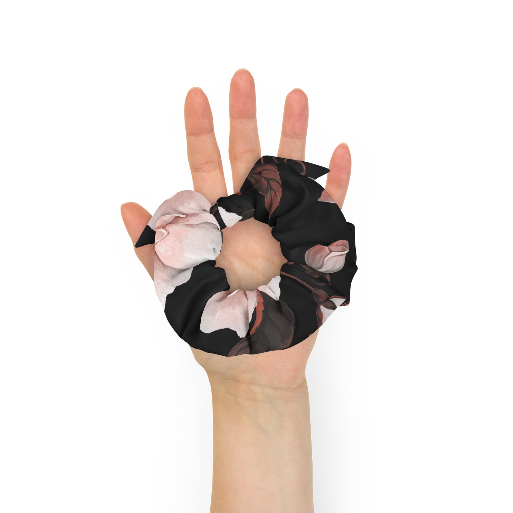The Paris Scrunchie.A recycled fabric hair scrunchie with a black base and a pink and white floral print, and removable bow shown being worn on a person's hand against a plain white background.