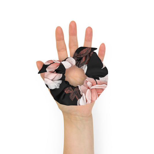 The Paris Scrunchie.A recycled fabric hair scrunchie with a black base and a pink and white floral print, and removable bow shown being worn on a person's hand against a plain white background.